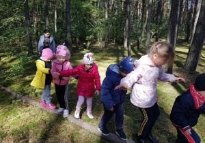 dzieci w lesie podczas przejścia po powalonym drzewie